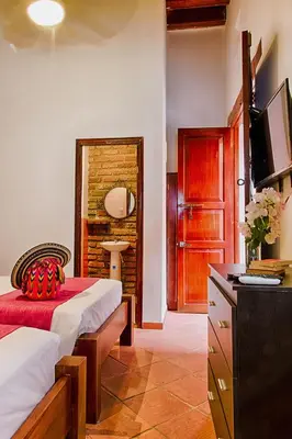 a bedroom with two beds and a television in it at Casa D´Remedios La Bella Hotel Boutique in Ciénaga