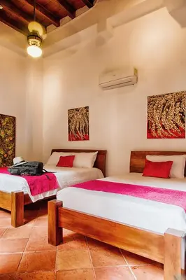 a bedroom with two beds and paintings on the wall at Casa D´Remedios La Bella Hotel Boutique in Ciénaga