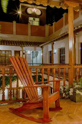 a wooden rocking chair sitting on a porch at Casa D´Remedios La Bella Hotel Boutique in Ciénaga