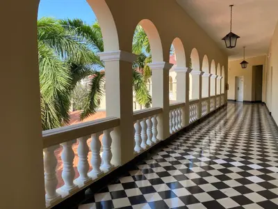 a hallway with a black and white checkered floor and windows at Hotel El Prado in Barranquilla