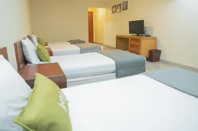 a hotel room with three beds and a television at Ayenda 1313 Barahona 72 in Barranquilla