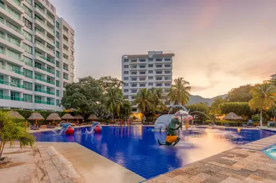 a person holding an umbrella in a swimming pool at GHL Relax Hotel Costa Azul in Santa Marta