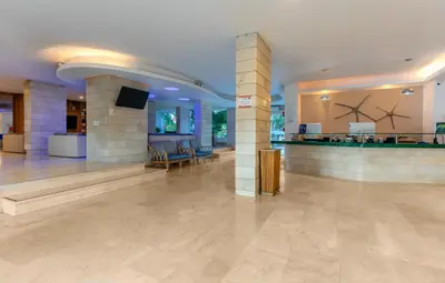 a lobby with columns and a tv in a building at GHL Relax Hotel Costa Azul in Santa Marta