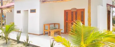 a small white house with a wooden door at Ecohotel Kocoluu in San Bernardo del Viento
