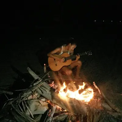 a man playing a guitar over a fire at Ecohotel Kocoluu in San Bernardo del Viento