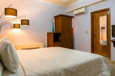 a bedroom with a white bed and a wooden cabinet at Hotel Casa La Tablada Manga in Cartagena de Indias
