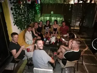 a group of people sitting around a table with drinks at Hostel la Antigua Capsula in Cartagena de Indias