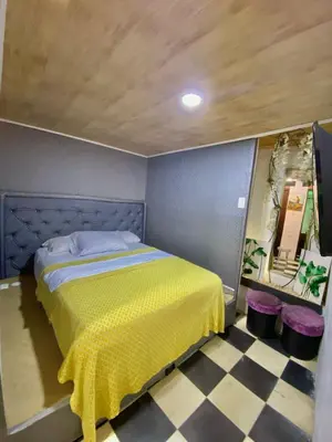a bedroom with a yellow bed with a checkered floor at Hostel la Antigua Capsula in Cartagena de Indias
