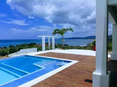 a house with a swimming pool and the ocean at Frente al Mar in Santa Veronica