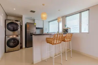 a kitchen with a bar with stools and a refrigerator at Escapada 5 estrellas frente al mar - sonest morros in Cartagena de Indias