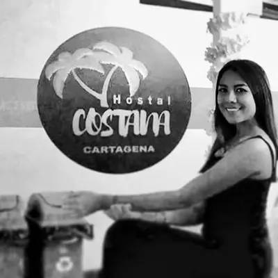 a woman is shaking hands in front of a sign at Costana - Hostal in Cartagena de Indias