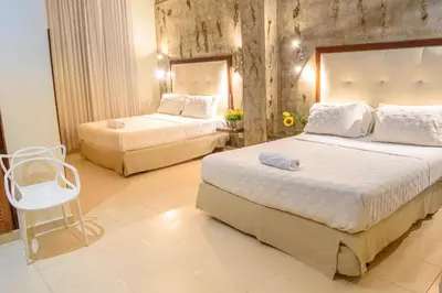 a hotel room with two beds and a chair at Hotel Virrey Cartagena in Cartagena de Indias