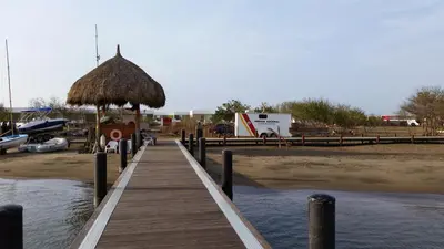 a wooden boardwalk leading to a dock on a beach at cabaña puerto velero in Puerto Caimán