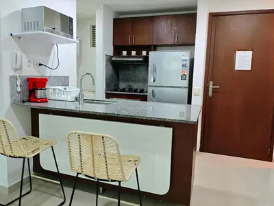 a kitchen with a counter with chairs and a refrigerator at Edificio Morros Vitri in Cartagena de Indias