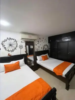 a bedroom with two beds with orange and white sheets at Casa Turística Realismo Mágico in Aracataca