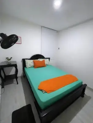 a bedroom with a bed with an orange blanket on it at Casa Turística Realismo Mágico in Aracataca