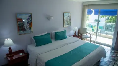 a bedroom with a large bed with green pillows at Hotel Bahia Cartagena in Cartagena de Indias