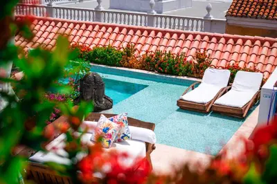 a swimming pool with two lounge chairs and a statue at Hotel Aguamarina Boutique in Cartagena de Indias