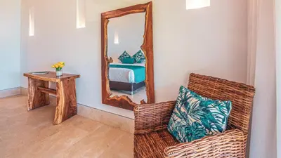 a living room with a wicker chair and a mirror at Aura Hotel Barú in Baru