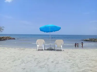 two chairs and a blue umbrella on a beach at Cabañas Los Juanchos Coveñas in Coveñas