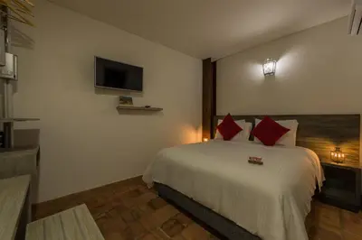 a bedroom with a bed with red pillows and a tv at Getsemani Cartagena Hotel in Cartagena de Indias