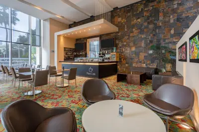 a waiting room with chairs and tables and a bar at Estelar Alto Prado in Barranquilla
