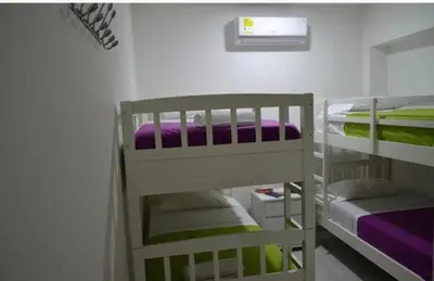two bunk beds in a room with purple and green sheets at Hostal Lumar in Barranquilla