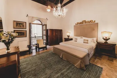 a bedroom with a large bed and a chandelier at Hotel Boutique Casa Del Arzobispado in Cartagena de Indias