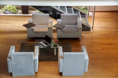 a lobby with chairs and a table with a laptop at NH Collection Royal Smartsuites in Barranquilla