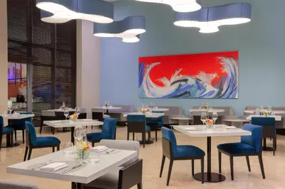 a dining room with tables and chairs and a painting at NH Collection Royal Smartsuites in Barranquilla