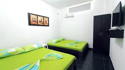 two beds in a small room with green sheets at Apartamento Aeromar, Santa Marta in Santa Marta