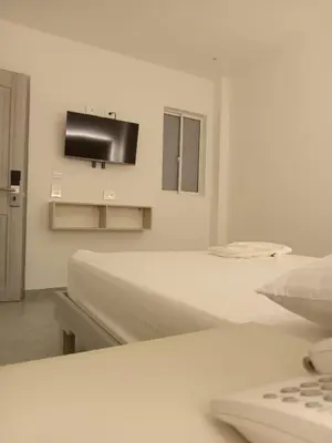 a room with two beds and a tv on the wall at Hotel San Sebastian Real in Cartagena de Indias