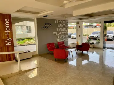 a lobby with red chairs and a sign on the wall at Apartamentos Oceana - Cerca al Buenavista by SOHO in Barranquilla