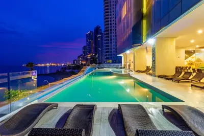 a swimming pool with chairs and a building at Hotel Cartagena Dubai in Cartagena de Indias