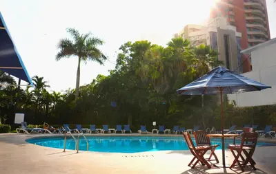 a swimming pool with chairs and an umbrella at Hotel Barranquilla Plaza in Barranquilla