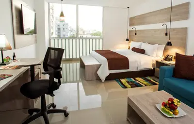 a hotel room with a bed and a desk and a chair at Hotel Barranquilla Plaza in Barranquilla