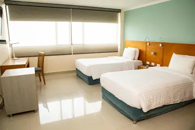 a hotel room with two beds and a window at Hotel Barranquilla Plaza in Barranquilla