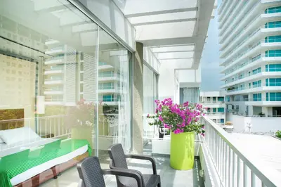 a balcony with chairs and a green bench and flowers at Hotel Santorini Resort in Santa Marta