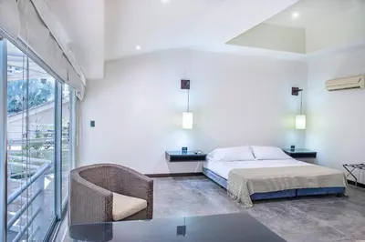 a bedroom with a bed and a table and a chair at Hotel Santorini Express y Cabañas in Santa Marta