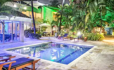a swimming pool in a building with palm trees at Hotel Santorini Express y Cabañas in Santa Marta