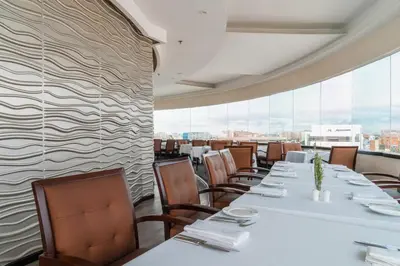 a restaurant with tables and chairs and a wall of windows at Hotel Dann Carlton Barranquilla y Centro de Convenciones in Barranquilla