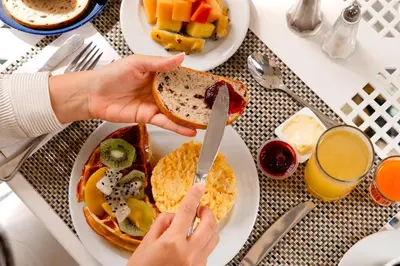 a table with plates of breakfast food and a person holding a knife at Hotel Dann Carlton Barranquilla y Centro de Convenciones in Barranquilla