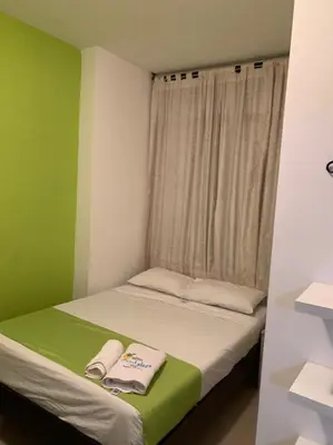 a small room with a bed with green and white at Hotel West Plaza in Santa Marta