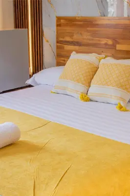 a bed with white sheets and yellow pillows on it at Hotel Casa Centenario Getsemaní in Cartagena de Indias