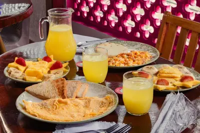 a table with plates of food and glasses of orange juice at Hotel Casa Centenario Getsemaní in Cartagena de Indias