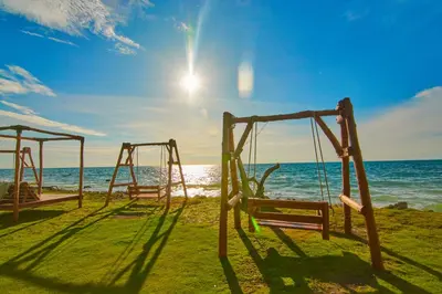 two swings on the beach with the ocean in the background at Hotel Isla Mucura in Isla Mucura