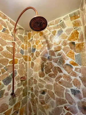 a shower in a bathroom with a stone wall at Hotel Isla Mucura in Isla Mucura