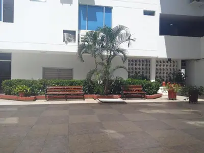 two benches in front of a building with a palm tree at Arriendos Yeny in Cartagena de Indias