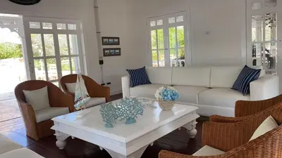 a living room with a white couch and chairs at Hotel Agua Azul Beach Resort in Baru