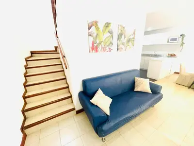 a blue couch in a living room with stairs at Casa de playa en Bello Horizonte a una cuadra del mar in Santa Marta